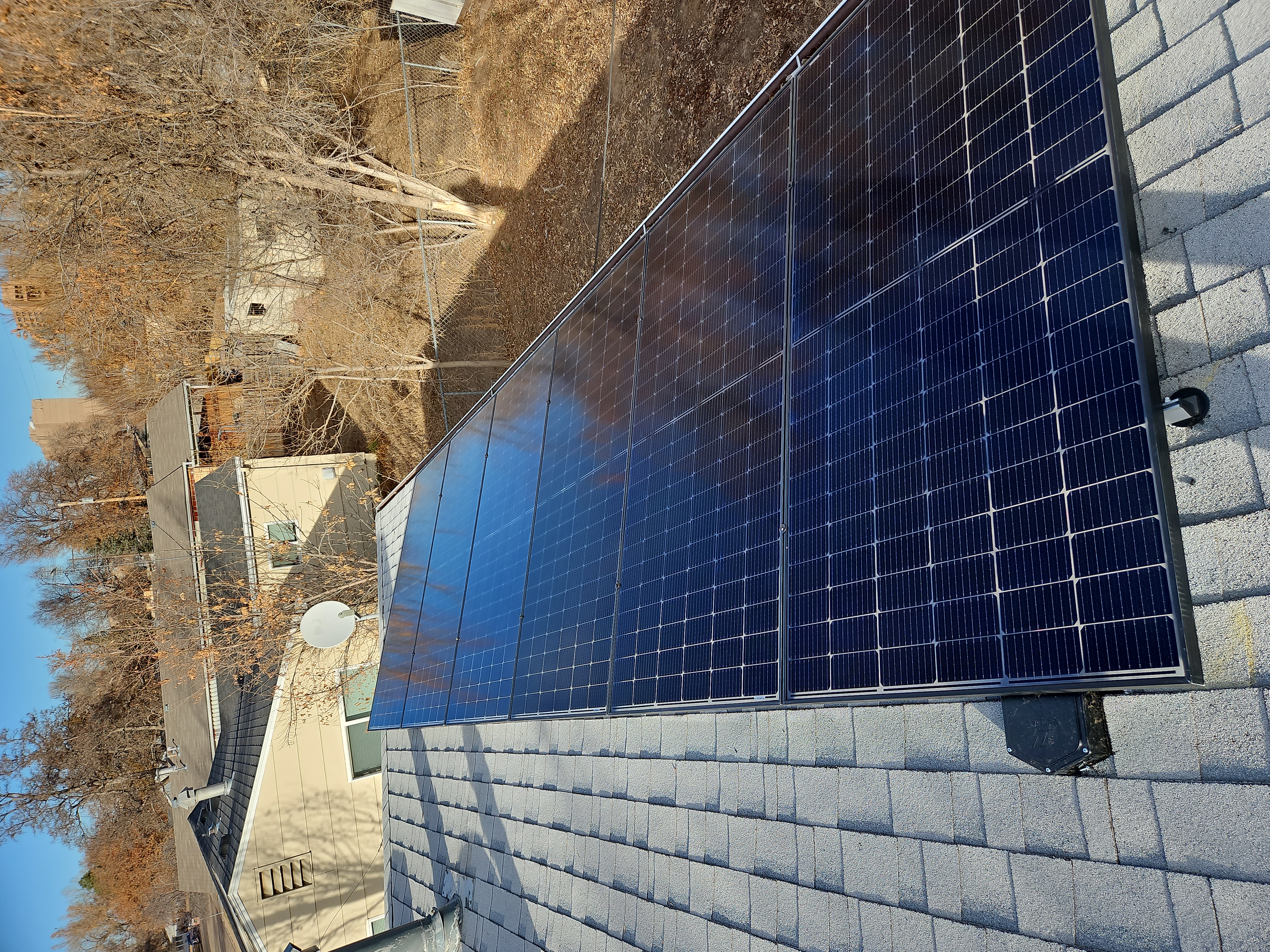 Solar panels installed on a roof with fall foliage in the background